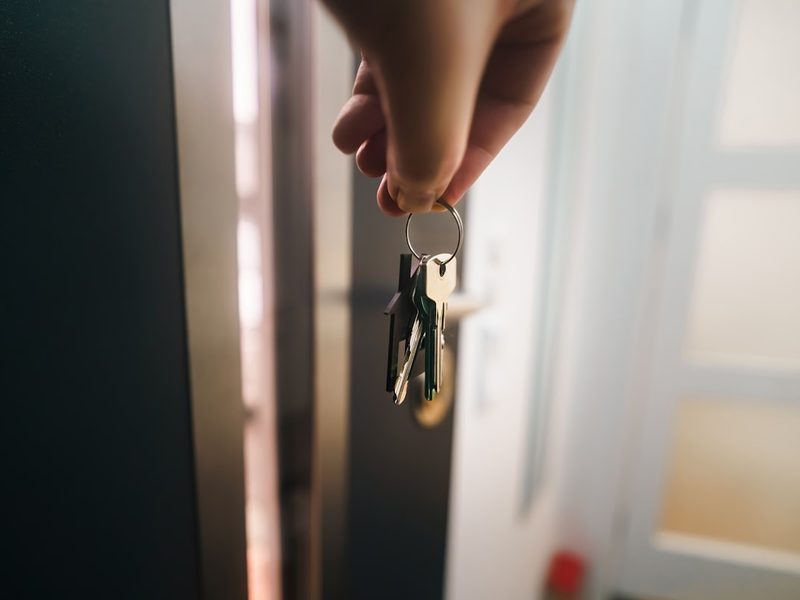 A hand holding keys at an open apartment door